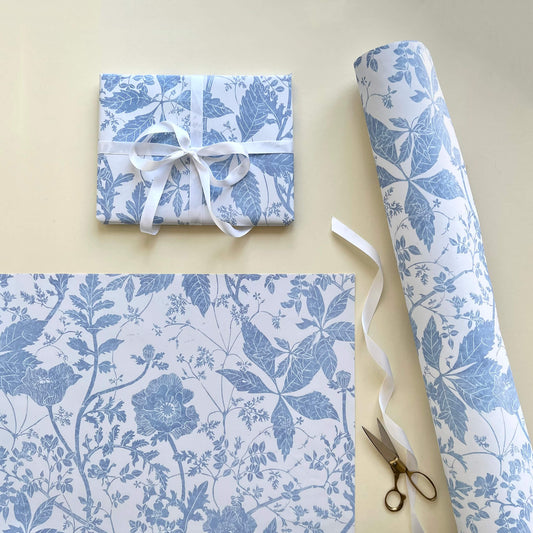Lino print gift wrap featuring poppy flowers leaves and wild roses in Delft blue and White by printmaker Laura Sowerby