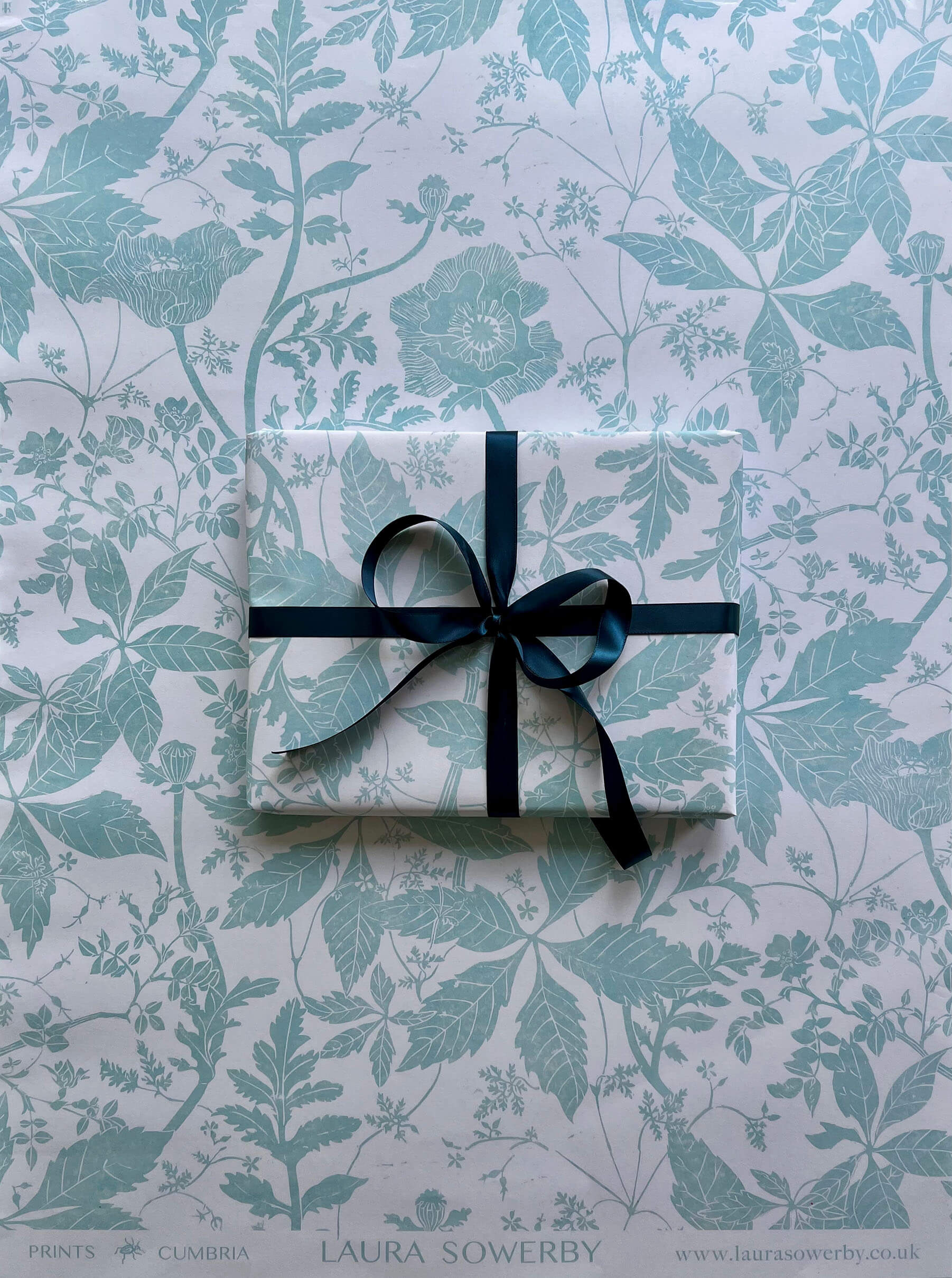 Lino print gift wrap featuring poppies and wild roses in green and white