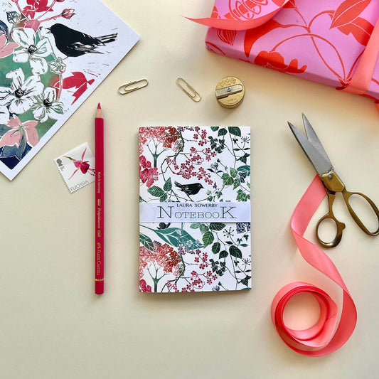Pocket notebook A6 size lino print cover in green and red with a black bird , ivy and hydrangea design